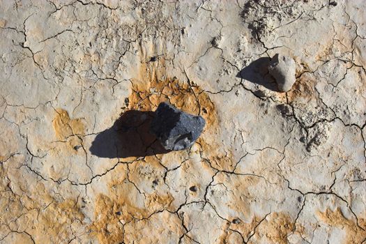 Fragment of black lava and ornage clay and salt mineral deposits in geological formations in Ubehebe Volcano, Death Valley National Park