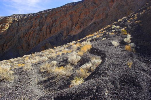 Fragment of black lava and ornage clay and salt mineral deposits in geological formations in Ubehebe Volcano, Death Valley National Park