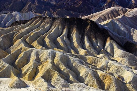 Desert landscape with multicolored yellow clay and salt mineral deposits in geological formations of Death Valley National Park