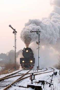 Old retro steam train starting from the station during wintertime