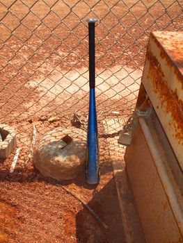 Baseball bat next to a fence.