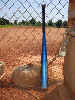 Baseball bat next to a fence.