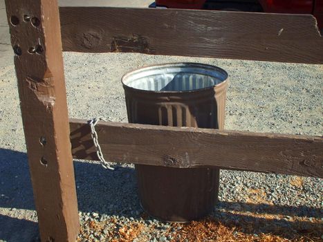 Recycle can on a sidewalk in a park.