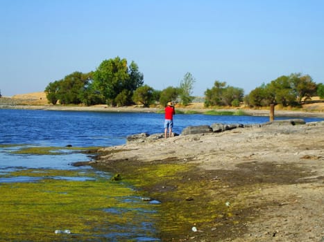 Fisherman fishing on a shore on a sunny day.