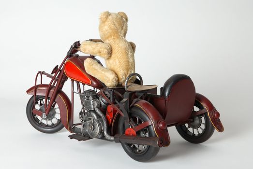 Teddy bear riding a toy motorbike