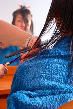 A hairdresser trimming a brunette woman in the salon