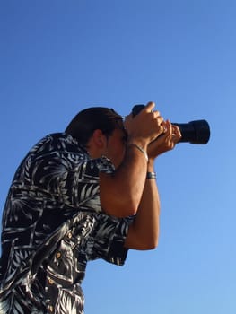 Young man photographer holding a photo camera outdoors.