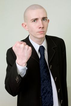 The young man in a suit threatens with a fist