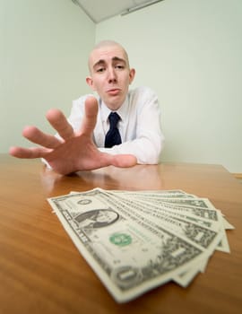 Young man reaches for a batch of money lying on a table