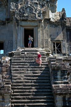 Tourists going down steep steps at Angkor Wat, Siem Reap, Cambodia. Angkor Wat, considered to be one of the Wonders of the World, is one of the most popular destinations in Southeast Asia and extremely important both historically and religiously.