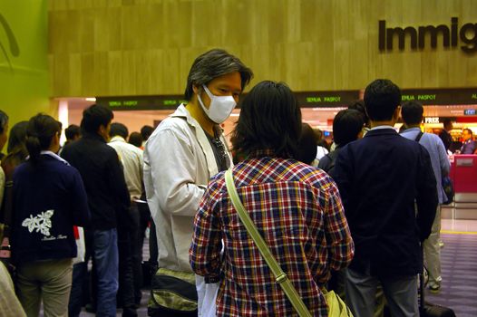 Passengers waiting in line at Singapore airport. Some passengers wear face masks, because of health scares, such as Swine flu, also known as h1n1 flu. Changi airport, Singapore. April 29, 2009