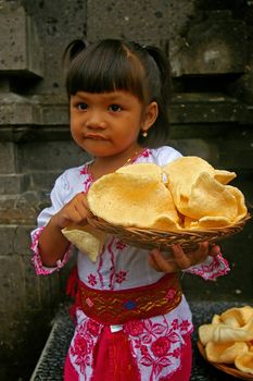 Balinese girl carrying a basket of Krupuk Udang, which is basically Prawn or Shrimp crackers, Bali, Indonesia.