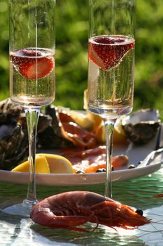 Champagne glasses with seafood platter in background, large prawn (shrimp) in foreground.