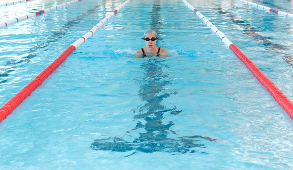 young woman swim on indoor pool. breastroke style.