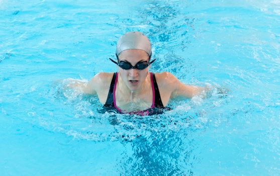 young woman swim on indoor pool close-up. Butterfly style.