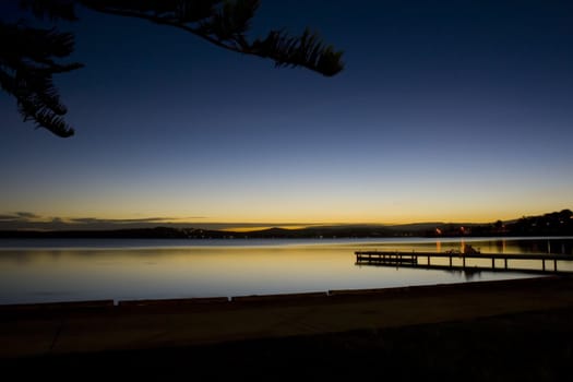 Peaceful long exposure overlooking calm water and a pier with children and bicycles.