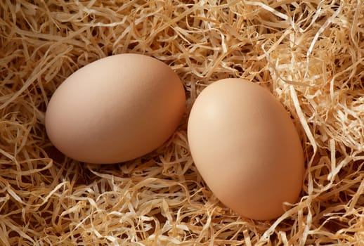 Two chicken eggs on straw.
