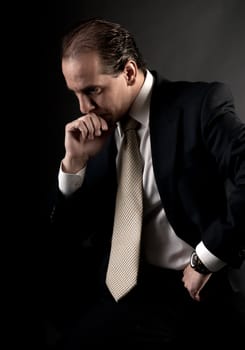 adult businessman serious thinking sitting on dark background