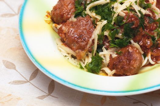 A dish with meatballs and spaghetti poured by sauce