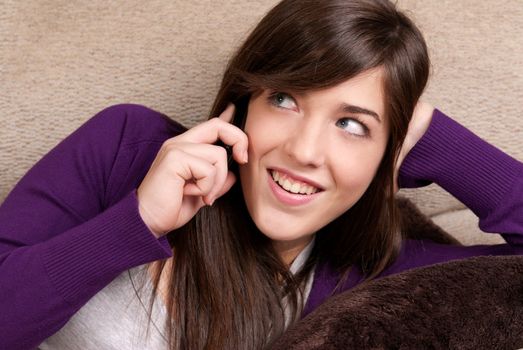 Young female talking by telephone laughing close-up lying on couch