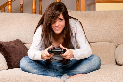 Young female concentrating playing videogames on sofa at home