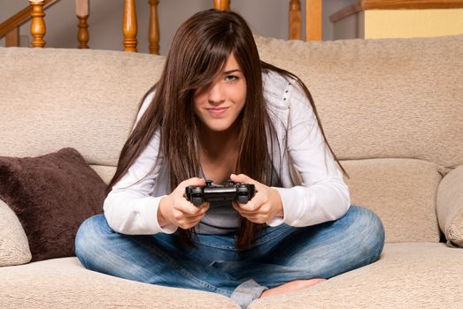 Young female concentrating playing videogames on sofa at home