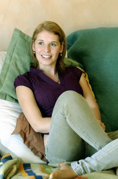 Pretty young woman sitting on couch, relaxing.