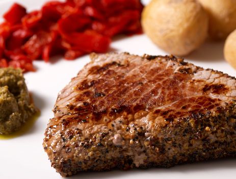 Beefsteak with pepper crust served with garnish and sauce