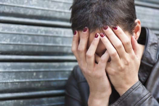 worried girl, hiding her face in his hands, his head bent down