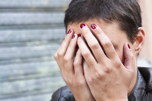 young woman concerned, her face hidden in her hands