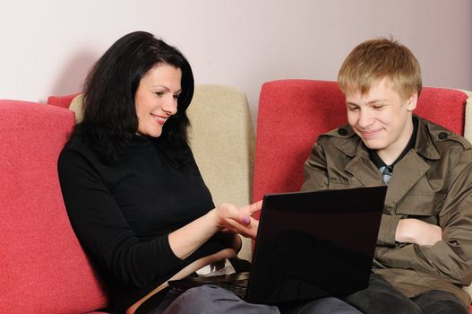 Mother and the son with a laptop sit on a sofa