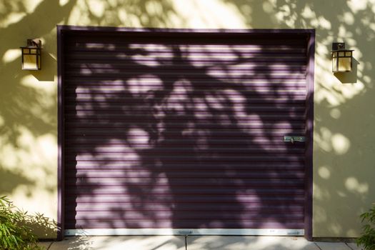 Purple Garage Door against yellow wall with tree shadows