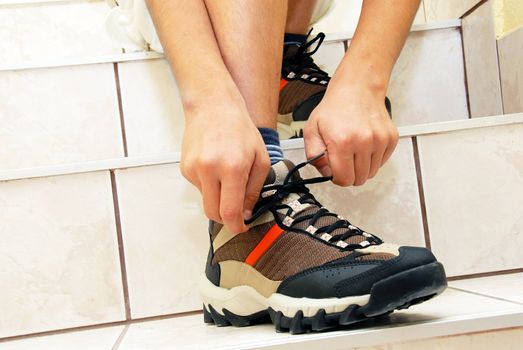 teen boy on stairs tying his shoe closeup