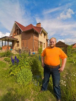 Self-satisfied man standing near his own house.