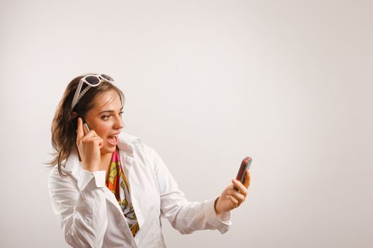 Modern looking young woman wearing white jacket talking on the phone