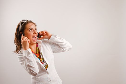 Modern looking young woman wearing white jacket talking on the phone