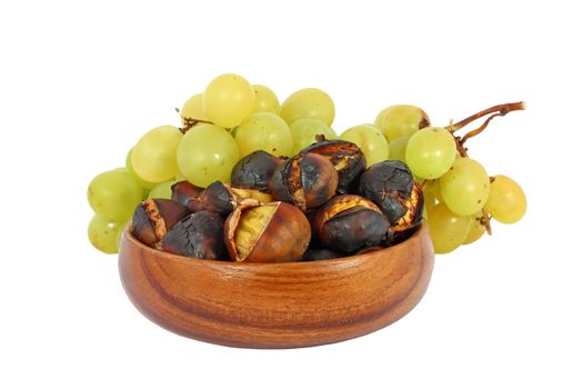 Roasted chestnuts in a wooden bowl and grape isolated on white