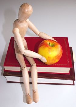 mannequin sitting on books with a apple for the teacher