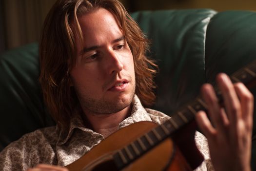 Young Musician Plays His Acoustic Guitar under Dramatic Lighting.