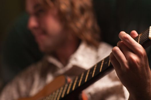 Young Musician Plays His Acoustic Guitar under Dramatic Lighting.