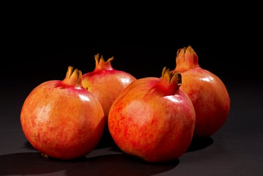 Four ripe bight red pomegranates on black