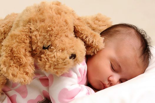 baby with white and pink sleepwear, sleeps with brown toy dog on her back