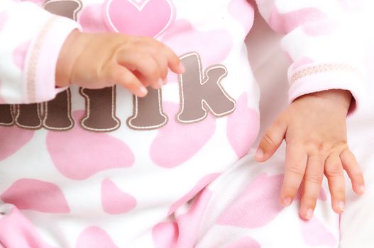 baby girl in pink and white clothes showing her small hands
