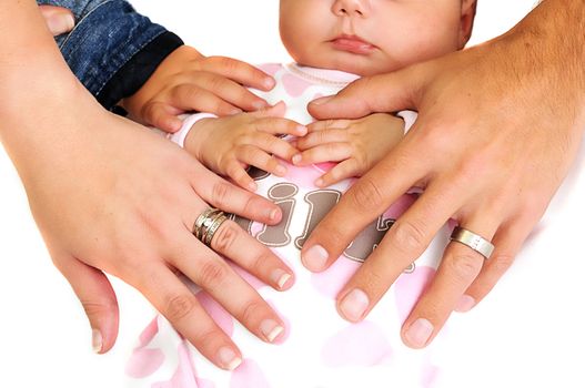 family placing hands on new baby girl with wedding rings visible