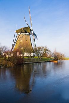 Dutch windmill in sunny frozen polder landscape