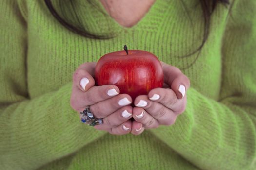 young woman holding healthy red apple in the hands - focus on the apple