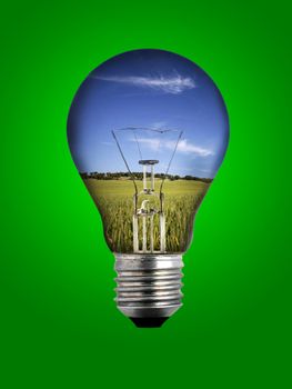 light bulb with landscape inside over green background - environmental concept