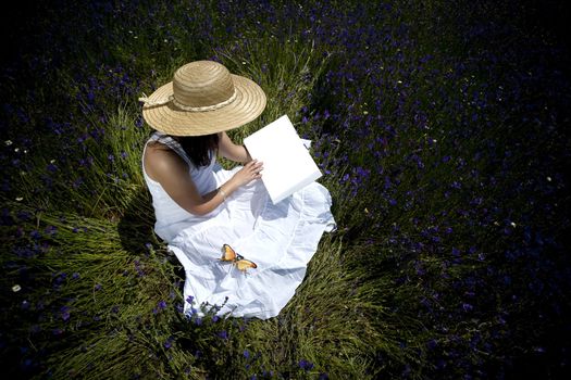 young woman in white dress reading book outdoors