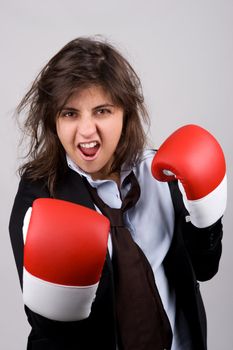 businesswoman wearing boxing gloves with confident attitude. grey background.