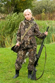 Blond girl in camouflage with a shotgun.